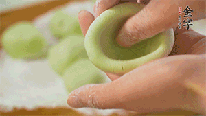 將均分的艾草面團(tuán)搓成圓，挖一個(gè)窩，放入餡心，再搓成圓。