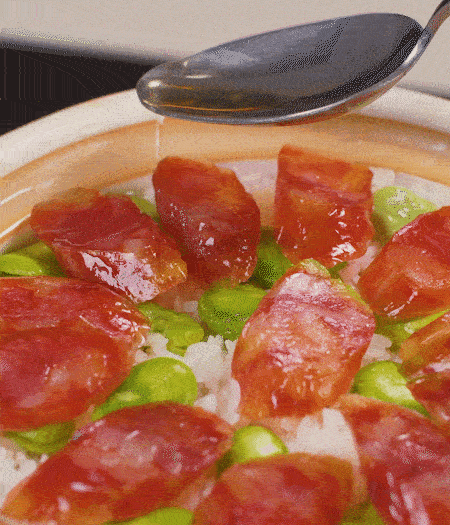 大米出現(xiàn)小孔時(shí)開(kāi)蓋放香腸，往鍋邊淋入少許油，再燜煮8~10分鐘左右。