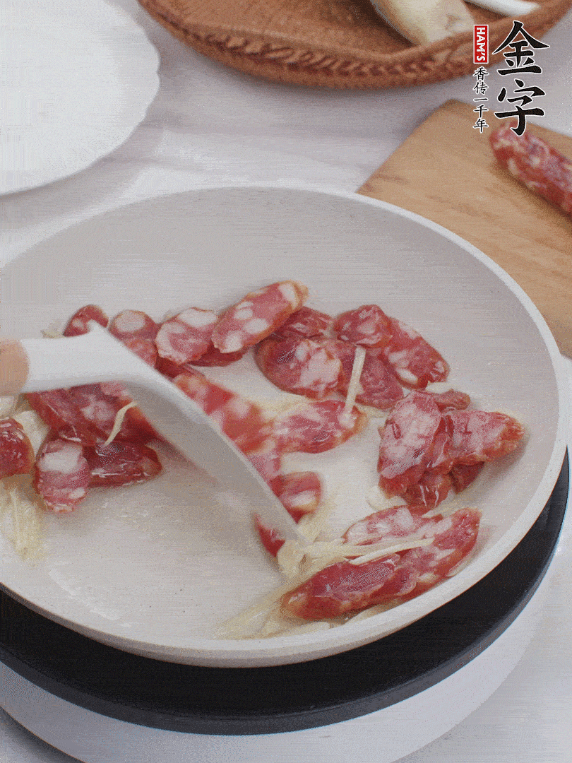 油溫3成熱時(shí)，下姜絲、蒜片、香腸炒出油脂。