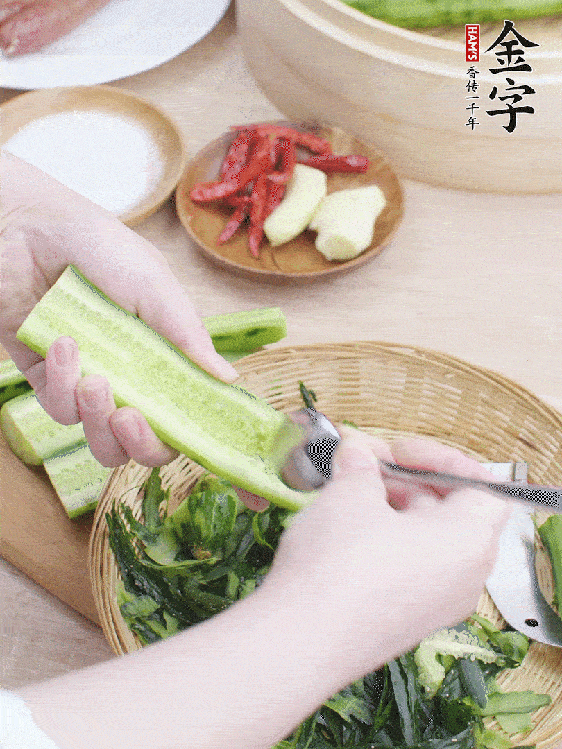 黃瓜削皮，對半切開，勺子挖去內(nèi)瓤，斜刀切片。青蒜斜刀切段。
