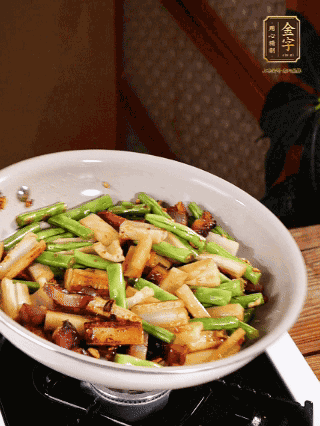 油熱下蒜末、干辣椒、醬肉煸炒出香味，依次下藕條、豆角翻炒均勻